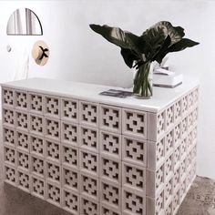 a vase with some flowers on top of a white dresser next to a mirror and clock