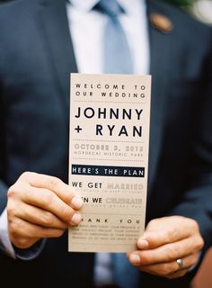 a man in a suit holding up a wedding card