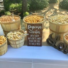 several buckets filled with popcorn sitting on top of a table next to a sign