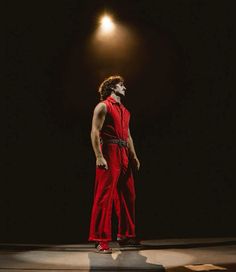 a man in red jumpsuits standing on stage with his head turned to the side