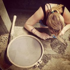 a woman sitting on the ground next to a drum and looking down at her instrument