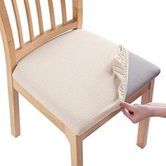 a person reaching for a pillow on top of a wooden chair