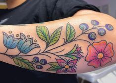 a woman's arm with flowers and leaves painted on the back of her arm