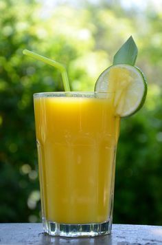 a glass filled with orange juice next to a slice of lime