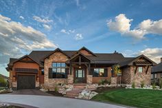 a large house with stone and brick accents on the front, driveway and grass area