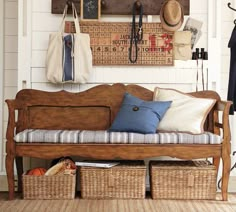 a wooden bench with baskets underneath it in front of a wall mounted coat rack and calendars on the wall