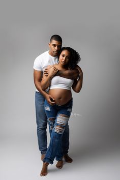 a man and woman are posing for the camera while holding each other's pregnant belly