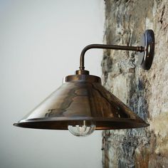 an old fashioned light hanging from the side of a stone wall