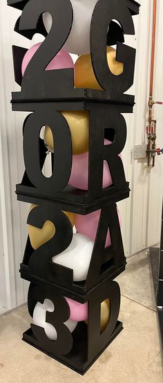 a large black and gold number sculpture sitting on top of a floor next to a white wall