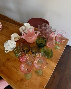 a wooden table topped with lots of glass cups and saucers on top of it