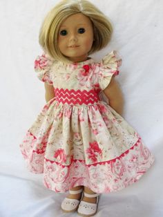 a doll with blonde hair wearing a pink and white dress on a white sheeted background