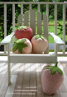 three strawberries and two peaches sitting on a white rocking chair with trees in the background