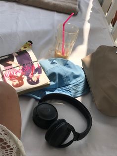 there is a hat, book and headphones on the bed