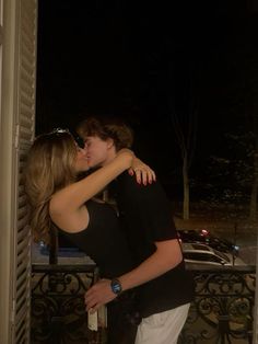 two people embracing each other in front of an open door at night with the lights on