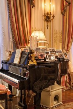 a grand piano in the middle of a living room with pictures on top of it