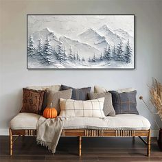 a living room with a white couch and paintings on the wall above it that have snow covered mountains in the background