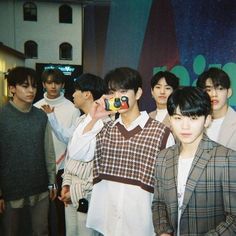 a group of young men standing next to each other in front of a wall with an advertisement on it