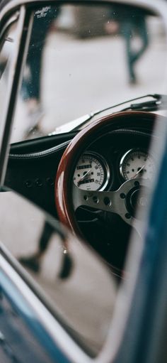 the interior of an old car is seen through the window, with gauges and steering wheel visible