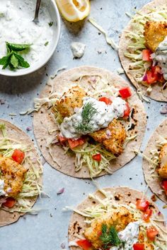 four fish tacos on tortillas with sour cream sauce and garnish