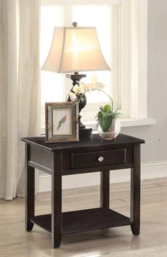 a small table with a lamp on top and flowers in vases next to it