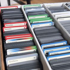 many folders are stacked on top of each other in a box with labels and name tags