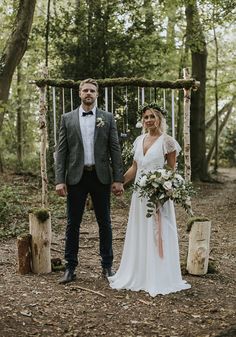 a bride and groom holding hands in the woods