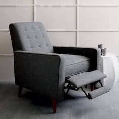 a gray chair sitting in front of a white wall