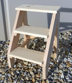 a wooden step stool sitting on top of gravel