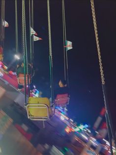 a carnival ride at night with people riding on swings and flags flying in the air