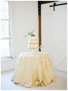 a wedding cake sitting on top of a table in front of a window with an open barn door