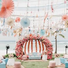 an outdoor seating area with flowers and umbrellas hanging from the ceiling, along with blue couches