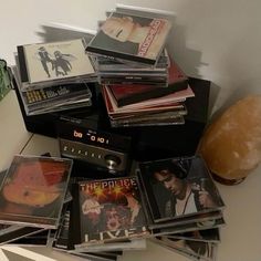 a pile of cd's sitting on top of a table next to a vase