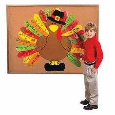 a young boy standing in front of a bulletin board with a turkey on it