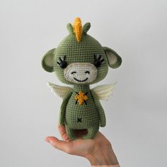 a crocheted stuffed animal in the shape of a dragon with wings and eyes