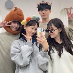 three young people posing for the camera with one holding up a cell phone in front of them