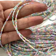 a hand holding a strand of multicolored glass beads