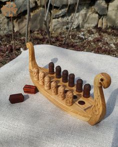 a wooden toy boat with eight small bottles on it's side and some rocks in the background