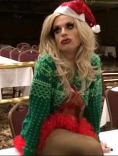 a woman sitting on top of a table wearing a santa hat and stockings with her legs crossed