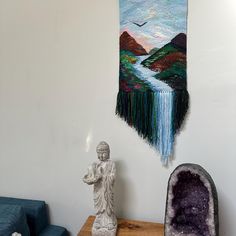 a room with a statue, couch and tapestry hanging on the wall next to it