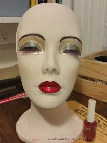 a white mannequin head with red lipstick and eyeliners on it's face