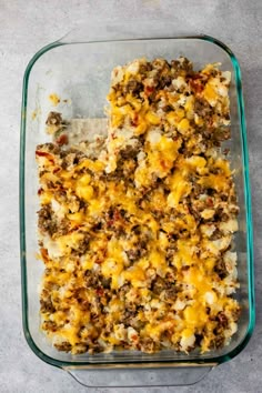 a casserole dish filled with ground beef, cheese and other toppings in a glass baking dish