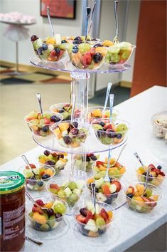 a table topped with lots of different types of fruit on top of glass bowls and spoons