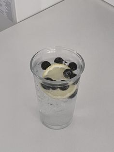 a glass filled with blueberries and lemon on top of a counter