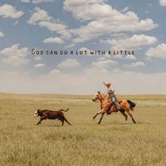 a man riding on the back of a brown horse next to a cow in a field