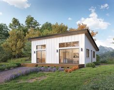 a small white house sitting on top of a lush green field next to a forest