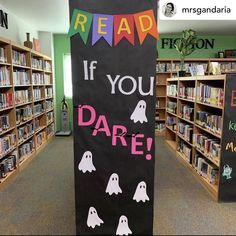 a sign that says read if you dare in front of bookshelves with halloween decorations