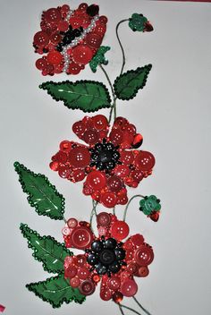 some red flowers and green leaves on a white surface