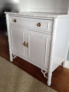 a white cabinet with gold handles and knobs on the doors is in a living room