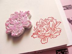 a stamp with a flower on it next to a piece of paper that has been cut out