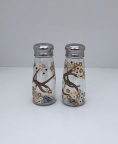 two glass salt and pepper shakers decorated with flowers